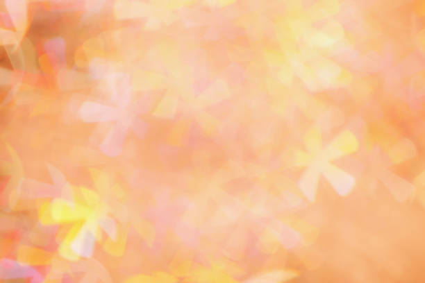 Defocused abstract bokeh background peach trend  color, flare from lights, color gradient, blurred figured bokeh as holiday texture. Glittering monochrome aesthetic textured lighting pattern