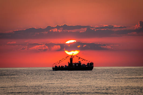 The sun setting behind a boat sailing on the ocean