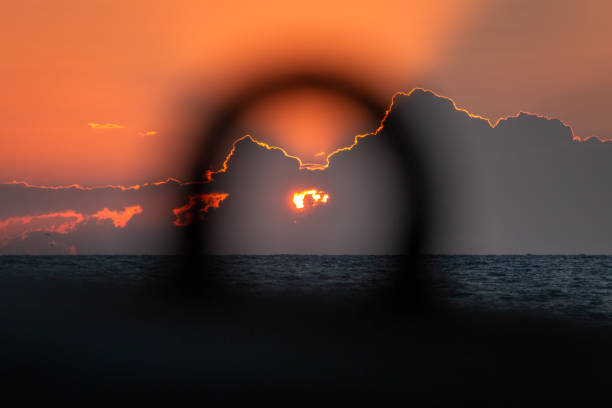 The sun setting on the ocean horizon from a sandy beach