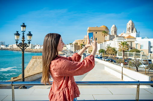 Beautiful tourist young woman selfie photo in Cadiz city skyline and beach in Andalusia of Spain