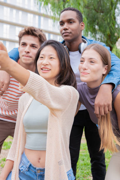 istock Vertical portrait Multiracial group of student friends laughing while taking a selfie 2111610696