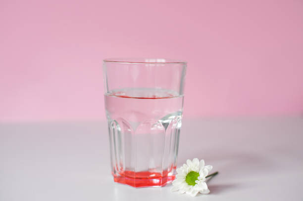 istock A transparent glass with drinking water stands on a pink background 2111620037