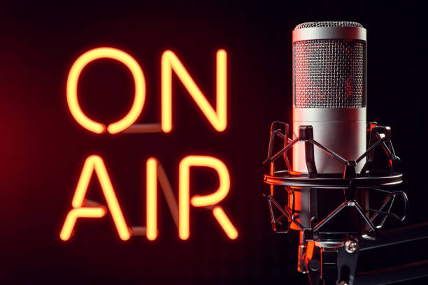 istock Professional silver microphone with orange illuminated ON AIR neon sign. 2111623173
