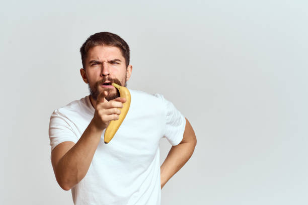 istock Cheerful man with a banana in his hands on a light background fun emotions Cropped view Copy Space 2111640147
