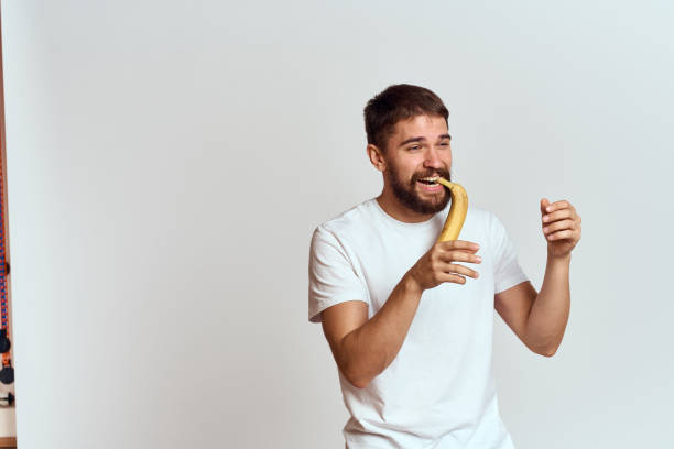 istock Cheerful man with a banana in his hands on a light background fun emotions Cropped view Copy Space 2111650672