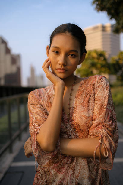 Portrait of Asian woman standing in nature looking at camera.