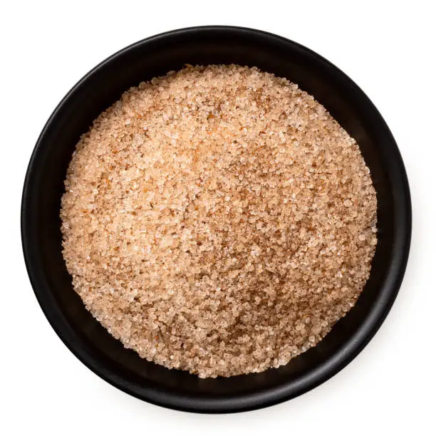 Cinnamon sugar in a black ceramic bowl isolated on white. Top view.