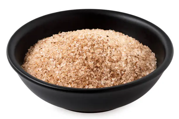 Cinnamon sugar in a black ceramic bowl isolated on white.