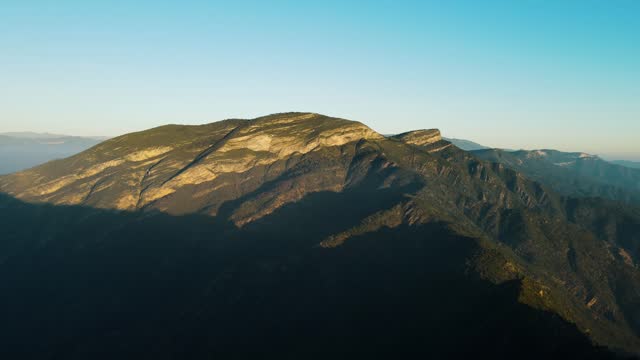 Sunlight revealing a majestic mountain topât sunrise with panoramic view on surrounding area, drone footage