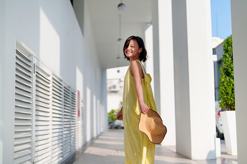 A cheerful solo Asian woman traveler, looks back with a beautiful smile while joyfully exploring Georgetown, Penang.