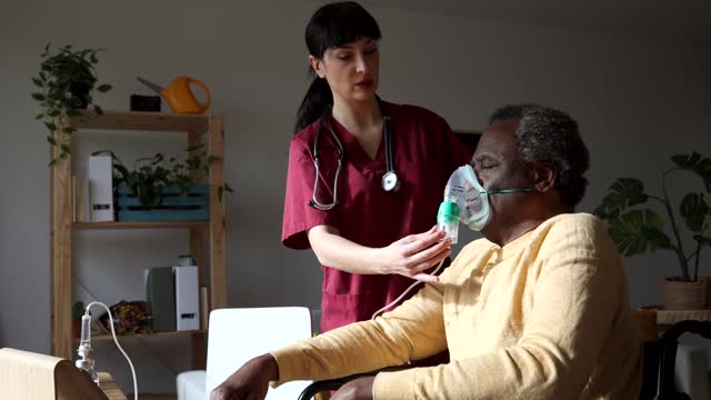 Elderly Man Receiving Oxygen Therapy with Nurse’s Help at Home