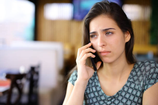 istock Sad woman talking on phone in a bar 2111732433