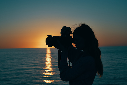 woman tourist holding professional camera on nature landscape sunset. High quality photo