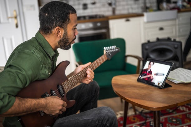 istock Man singing and learning to play guitar with tablet 2111745917