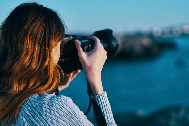 istock woman with camera on nature sea landscape 2111746449