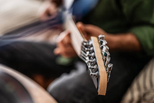 A detail shot of a neck of a western guitarin front of a grey background.