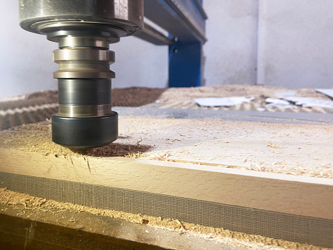 Close-up of CNC machine rotary blade cutting wood for manufacturing