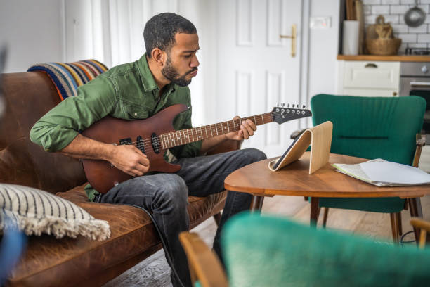 istock Man singing and learning to play guitar with tablet 2111752202