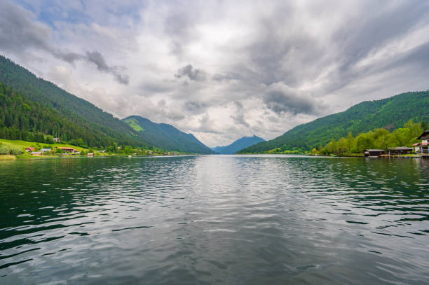 Weissensee or Weißensee lake in Carinthia in Austria within the Gailtal Alps mountain range during an overcast springtime day.