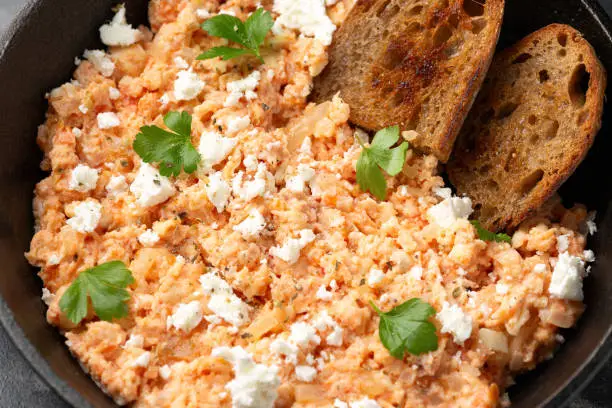 Strapatsada, eggs scrambled with bread, tomatoes and feta cheese in iron cast pan. Greek breakfast.