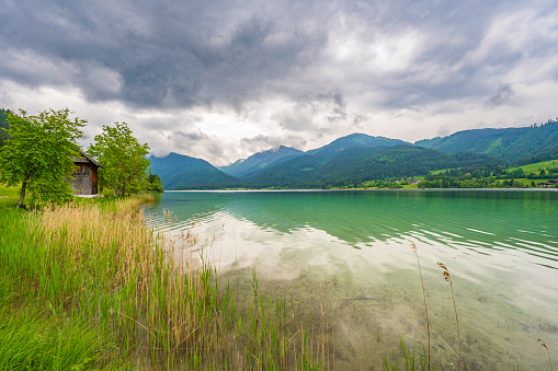 Weissensee or Weißensee lake in Carinthia in Austria within the Gailtal Alps mountain range during an overcast springtime day.