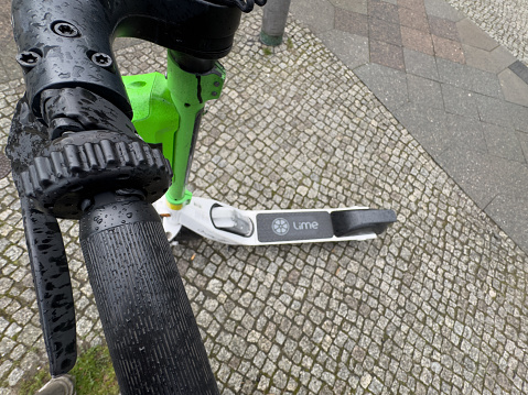 Lime scooters parked outdoors in Prenzlauer Berg, Berlin, Germany, next to a bicycle lane. No people.