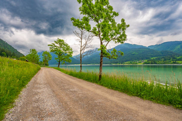 Footpath along the Weissensee or Weißensee lake in Carinthia in Austria within the Gailtal Alps mountain range during an overcast springtime day.