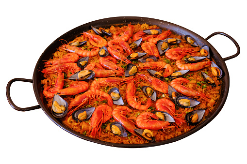 Spanish national dish paella in a large frying pan isolated on a white background, top view.