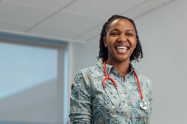 Happy to be Helping People Portrait shot of a female general practitioner standing looking into the camera while laughing. She has a stethoscope around her neck. doctor general practitioner stock pictures, royalty-free photos & images