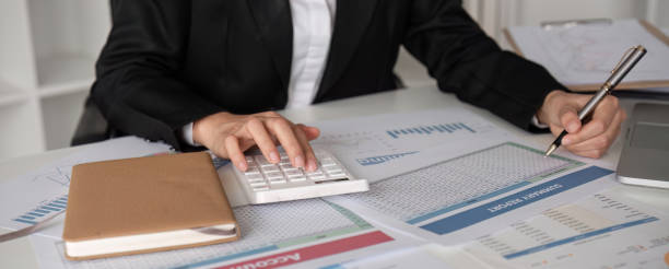 istock Close up, A young accountant calculates financial figures and company spending graphs using a calculator and laptop to take notes. 2111795763
