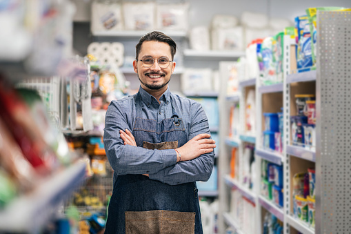 Portrait of successful smiling mature businessman wearing glasses with arms crossed. Domestic cleaning product background