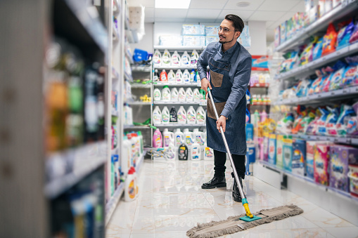 Business owner is cleaning the floor in a shop