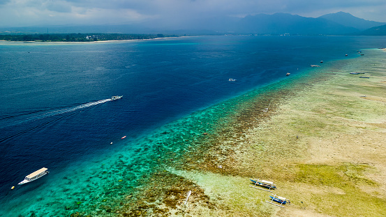 A huge, long fringing coral reef wll at low tide on a stormy afternoon (Gili Islands, Indonesia)