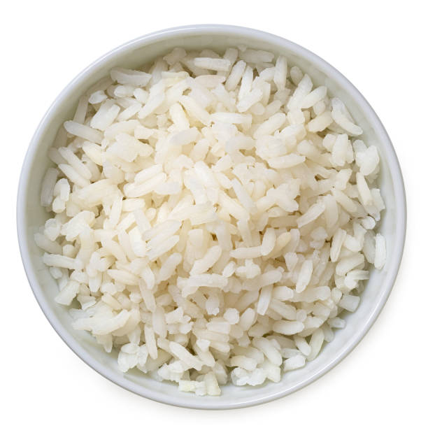 Cooked white rice in a white ceramic bowl isolated on white from above. Cooked white rice in a white ceramic bowl isolated on white. Top view. rice food staple stock pictures, royalty-free photos & images