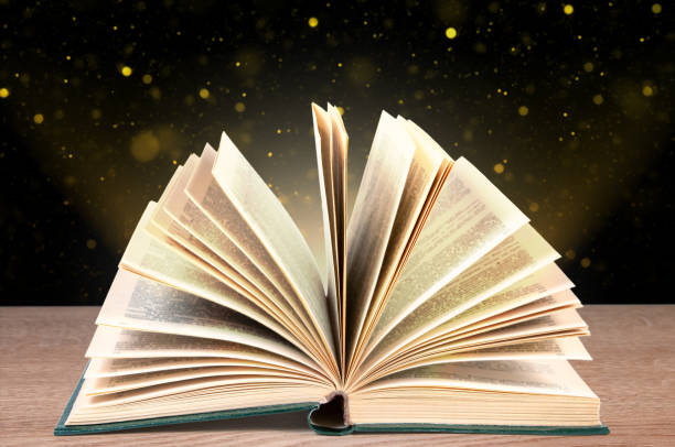 istock Fold-out book on a wooden surface against a dark background with bokeh. 2111826637