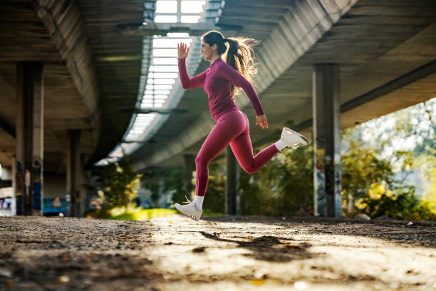 istock An urban female runner is jumping and running under the bridge. 2111863201