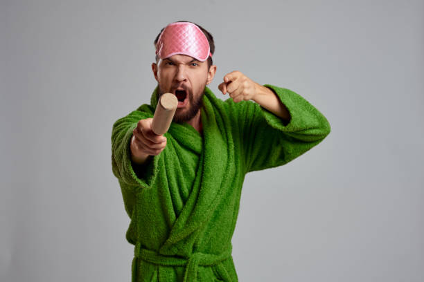 istock man with rolling pin in hand green robe pink sleep mask cropped view 2111864255