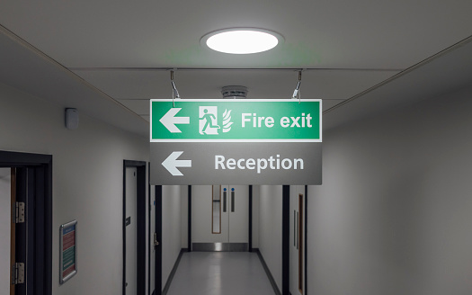 Close up shot of a sign for a fire exit and reception hanging from the ceiling in a hospital in Newcastle Upon Tyne.