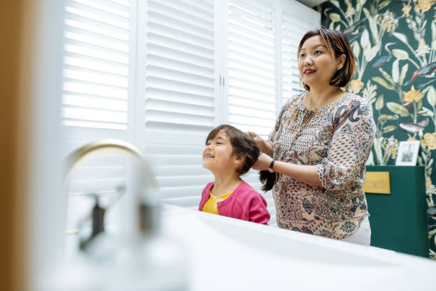 istock Morning routine in bathroom before school. Mother brushing daughter's hair 2111888794