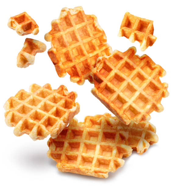 Belgian waffles and waffle pieces levitating in air on white background.
