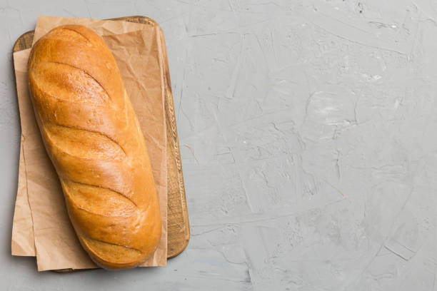 istock freshly baked bread with napkin on rustic table top view. Healthy white bread loaf isolated 2111894238