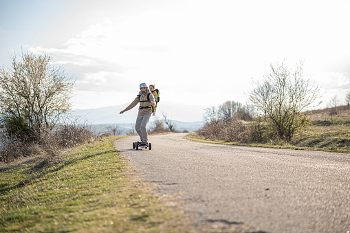 Family urban commute. Father and Gen Alpha daughter riding electric longboard.