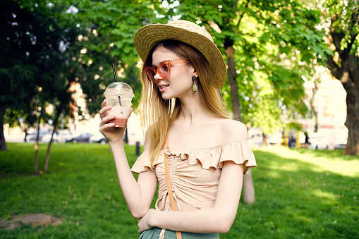 pretty woman walks in the park outdoors with a drink Fresh air. High quality photo