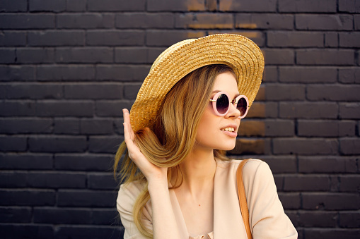 attractive woman on the street wearing hat and glasses black brick wall. High quality photo