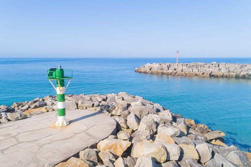 view of a small lighthouse on pier breakwater against quiet sea