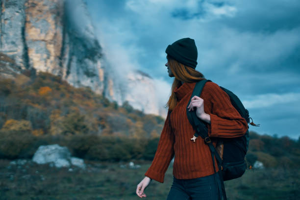 istock Traveler in a sweater with a backpack on her back tourism clouds sky landscape 2112017796