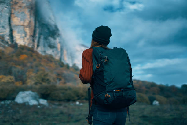 istock Traveler in a sweater with a backpack on her back tourism clouds sky landscape 2112037348