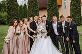 full-length portrait of the newlyweds and their friends at the wedding. The bride and groom with bridesmaids and friends of the groom are having fun and rejoicing at the wedding.