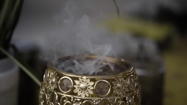 Incense fragrant smoke drifting from a golden burner in slow motion
