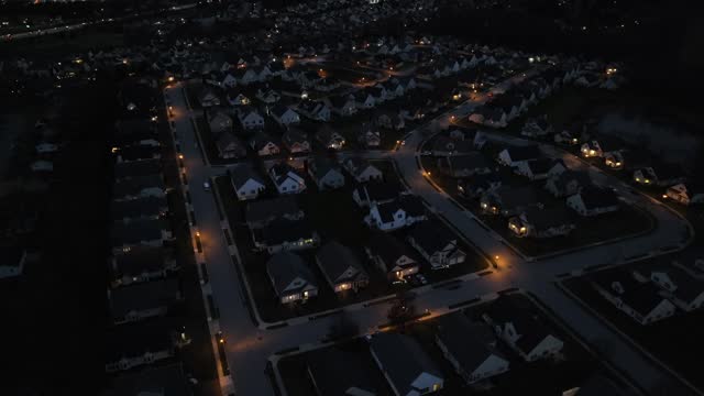 High aerial shot of dark neighborhood at night. Development with house and street lights in USA housing area.